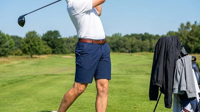A golfer wearing tailored, above-the-knee golf shorts on a sunny day