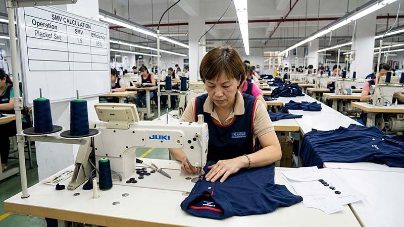 A worker sewing a golf polo on an industrial sewing machine.