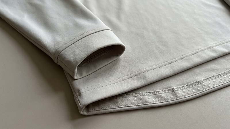 A close-up on the cuff and hem of a performance quarter-zip.