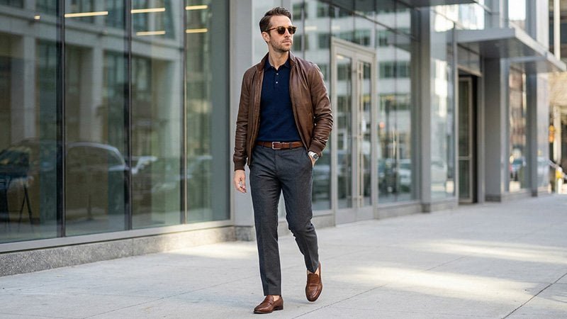 Finishing touches for a polo shirt outfit A man wearing a polo under a bomber jacket, with attention to the belt and shoes