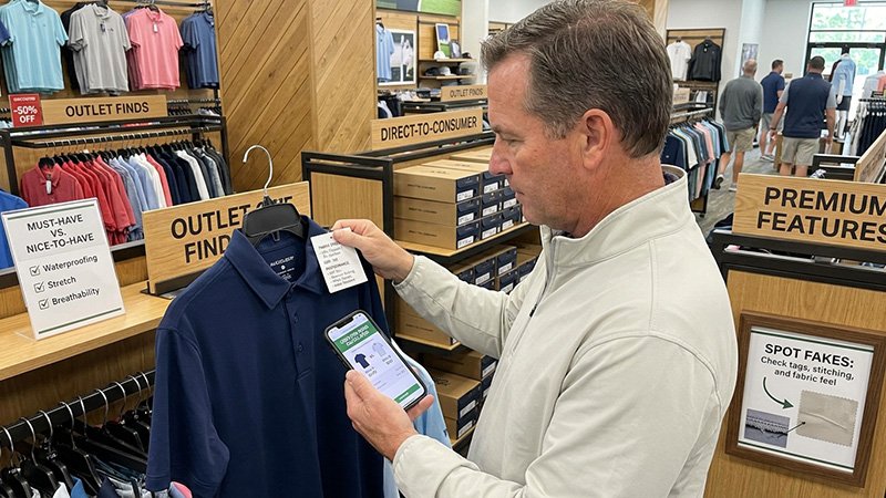 How to Buy Golf Apparel Smarter A person closely examining the fabric and tag on a golf polo in a store.